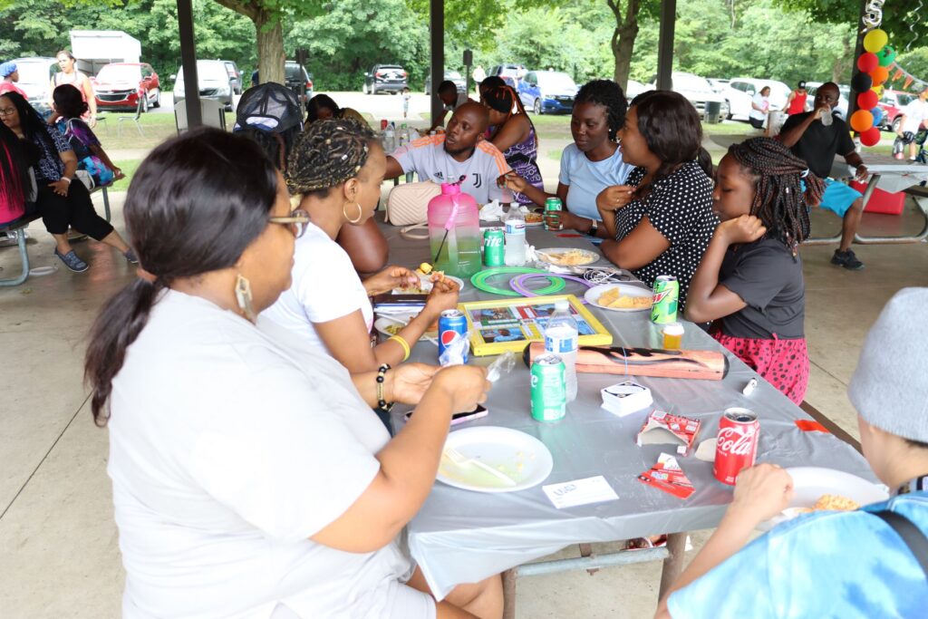 Church members share a meal together at picnic tables in the park