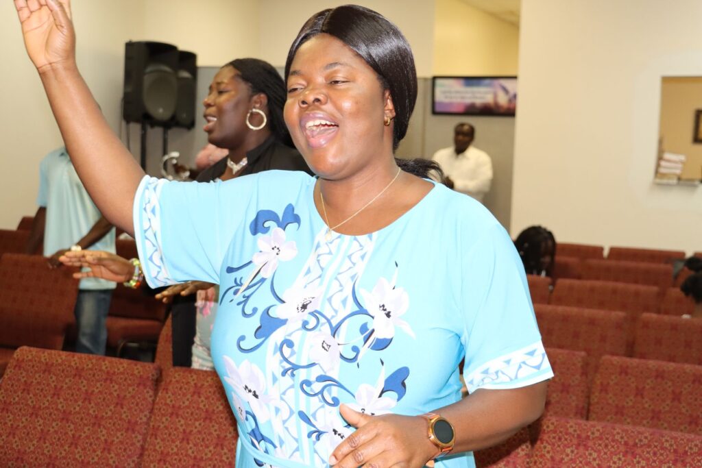 A woman raises her hand and sings in worship during a Sunday service at Faith Klinik Ministries