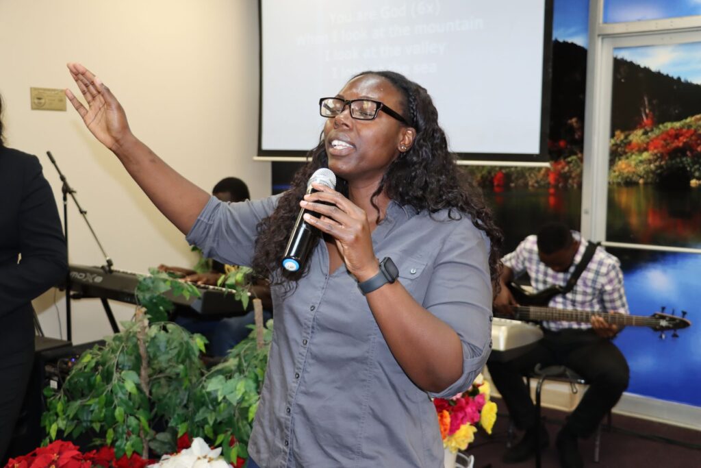 A worship leader lifts her hand in praise while singing at Faith Klinik Ministries